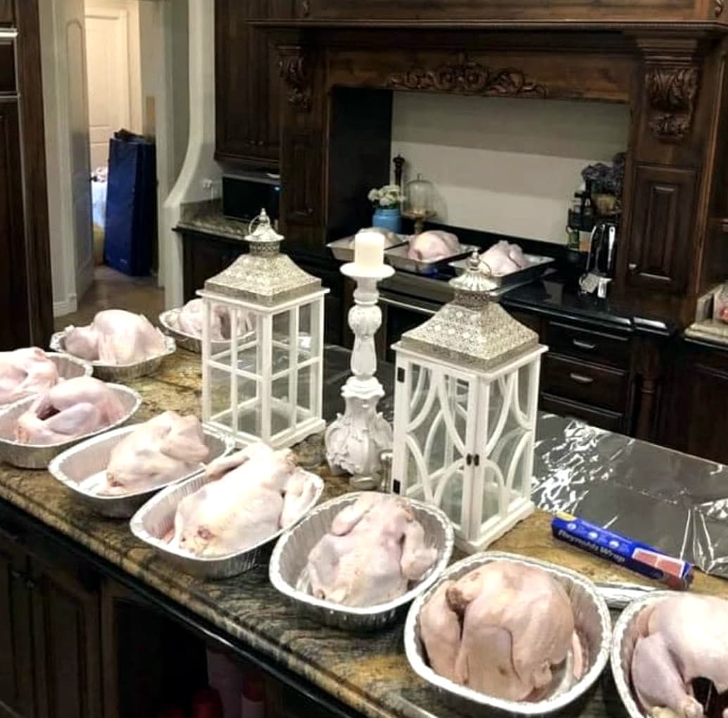 Turkeys in roasting pans lined up on a kitchen island before the dinner